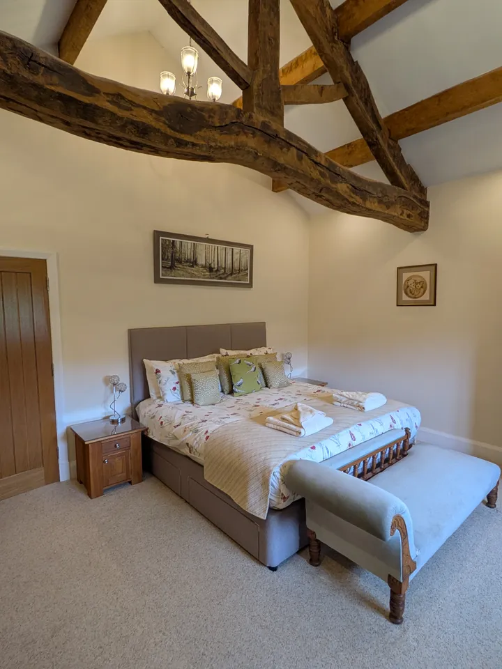 Master bedroom with exposed oak beams at Hill Brook Barn