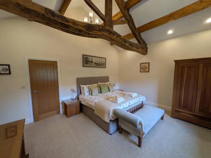 Master bedroom with exposed oak beams at Hill Brook Barn