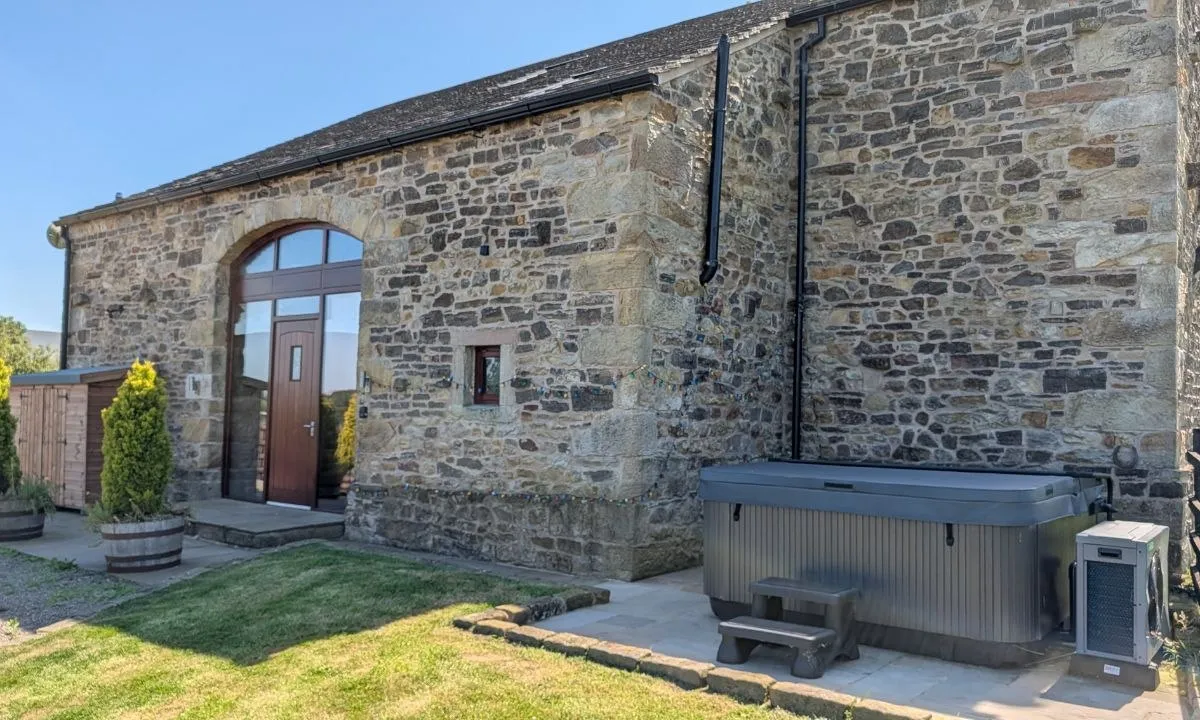Hill Brook Barn — the hot tub and stone exterior on a sunny day