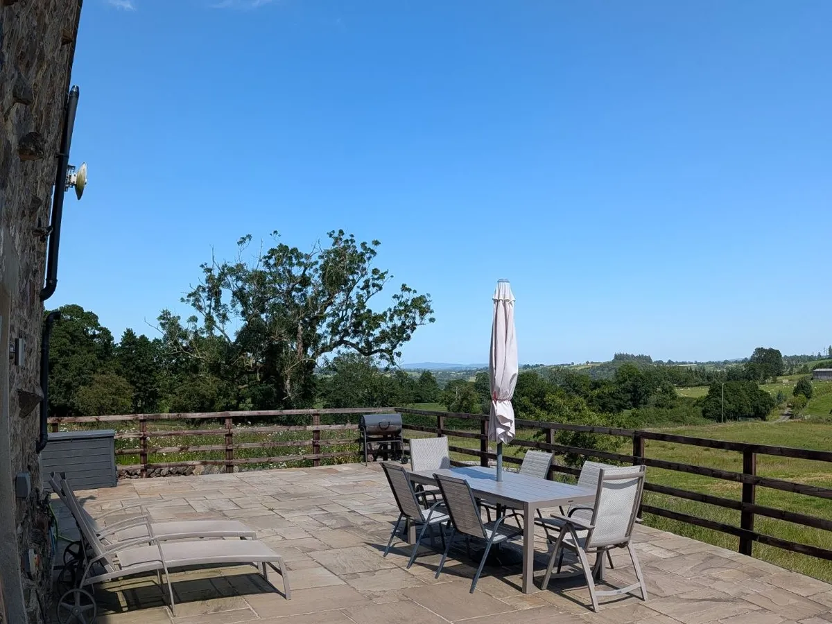 The full stone terrace with dining, loungers, and countryside views